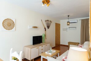 Een woonkamer met een televisie, een houten kast, een cactus en een eettafel.