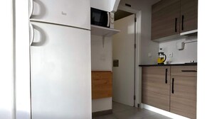 A kitchen with white appliances, wooden cabinets, and a tiled floor.