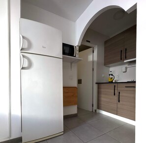 Kitchen area with refrigerator, microwave, and cabinets.