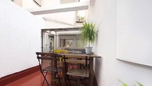 A small outdoor patio with a table and chairs, a potted plant, and a white wall. - Spacious Apartment, Seneca 1A next to the Center. (Málaga)