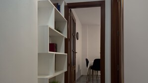 A hallway with a white bookshelf, a wooden door, and a dining area with a table and chairs. - Spacious Apartment, Seneca 1A next to the Center. (Málaga)