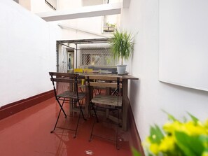 A small outdoor patio with a table and chairs, a potted plant, and a white wall. - Spacious Apartment, Seneca 1A next to the Center. (Málaga)