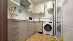 Uma cozinha compacta com máquina de lavar, micro-ondas e pia.