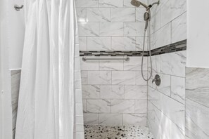 Eine Dusche mit Handbrause, Handtuchhalter und Fliesenboden.