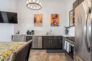 A modern kitchen with a dishwasher, stove, and refrigerator. There is a dining area with a table and chairs. - Tropical Retreat with Ocean View Oasis + Pool (Luquillo)
