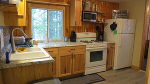 Une cuisine avec des meubles de rangement en bois, un évier, une cuisinière, un four à micro-ondes et un réfrigérateur.