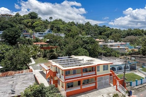 A multi-story building with balconies, surrounded by lush greenery and other buildings. - Tropical Oasis Retreat & Infiniti Pool (Luquillo)