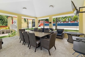 A covered patio area with a dining table, chairs, and a sofa. - Tropical Oasis Retreat & Infiniti Pool (Luquillo)
