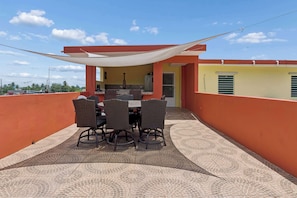 Un patio con una mesa y sillas, una zona de cocina y una pared amarilla.
