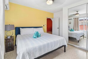 Una habitación de hotel con una cama, mesita de noche, lámpara y espejo.