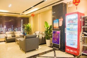 A hotel lobby with seating, a vending machine, and a large window with a city view. - Fubang Hotel (Yichun)