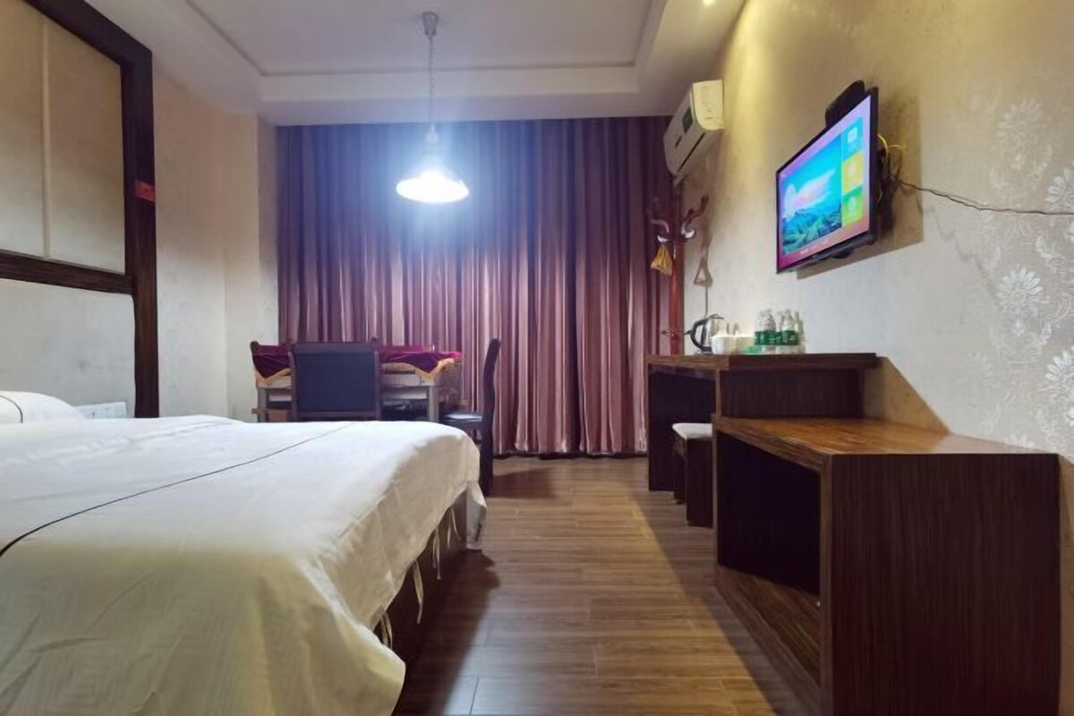 A hotel room with a bed, a desk, a chair, a television, and a curtain.