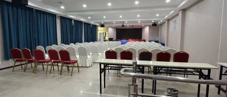 A conference room with rows of chairs, tables, and a stage area.