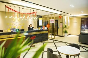 A hotel reception area with a reception desk, a receptionist, and a seating area with a table and chairs. - Fubang Hotel (Yichun)