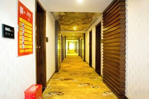 A hotel corridor with patterned carpet, wooden doors, and a red informational poster on the left wall. - Fubang Hotel (Yichun)