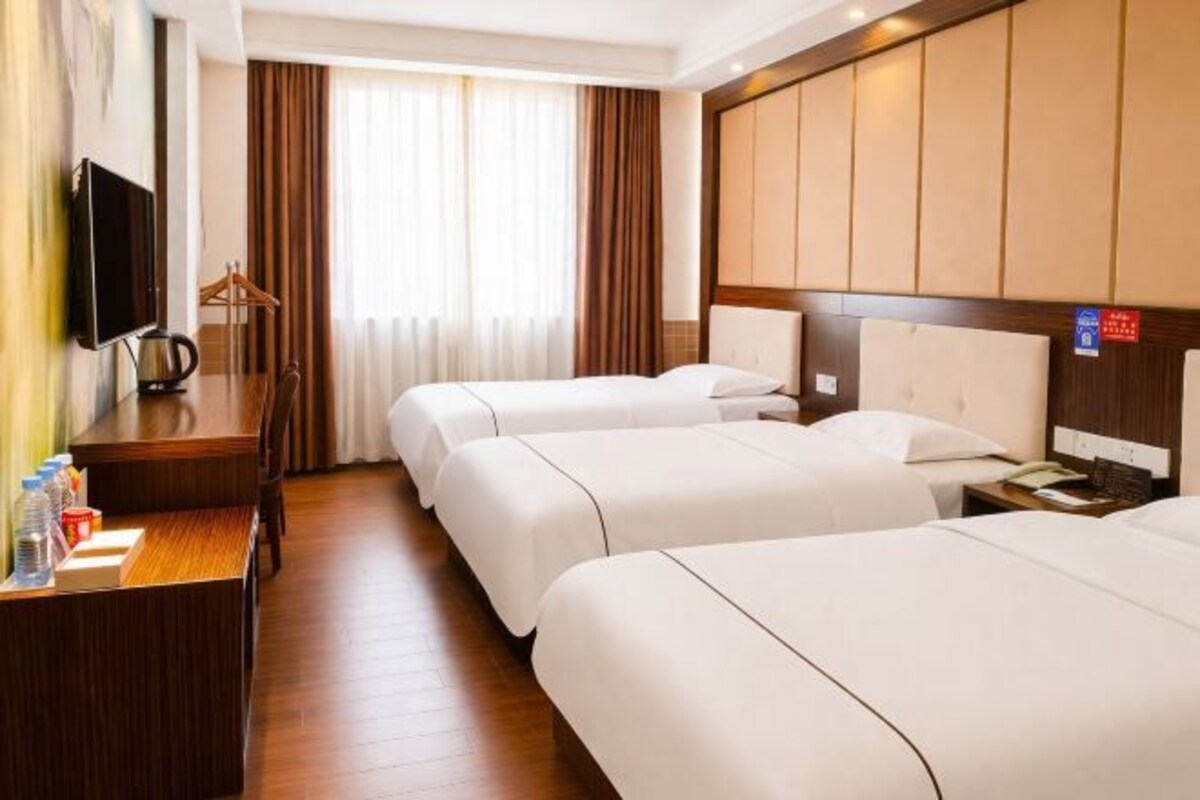 A hotel room with two beds, a desk with a TV, and a minibar.