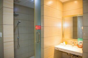 Un baño con ducha, lavamanos y espejo.