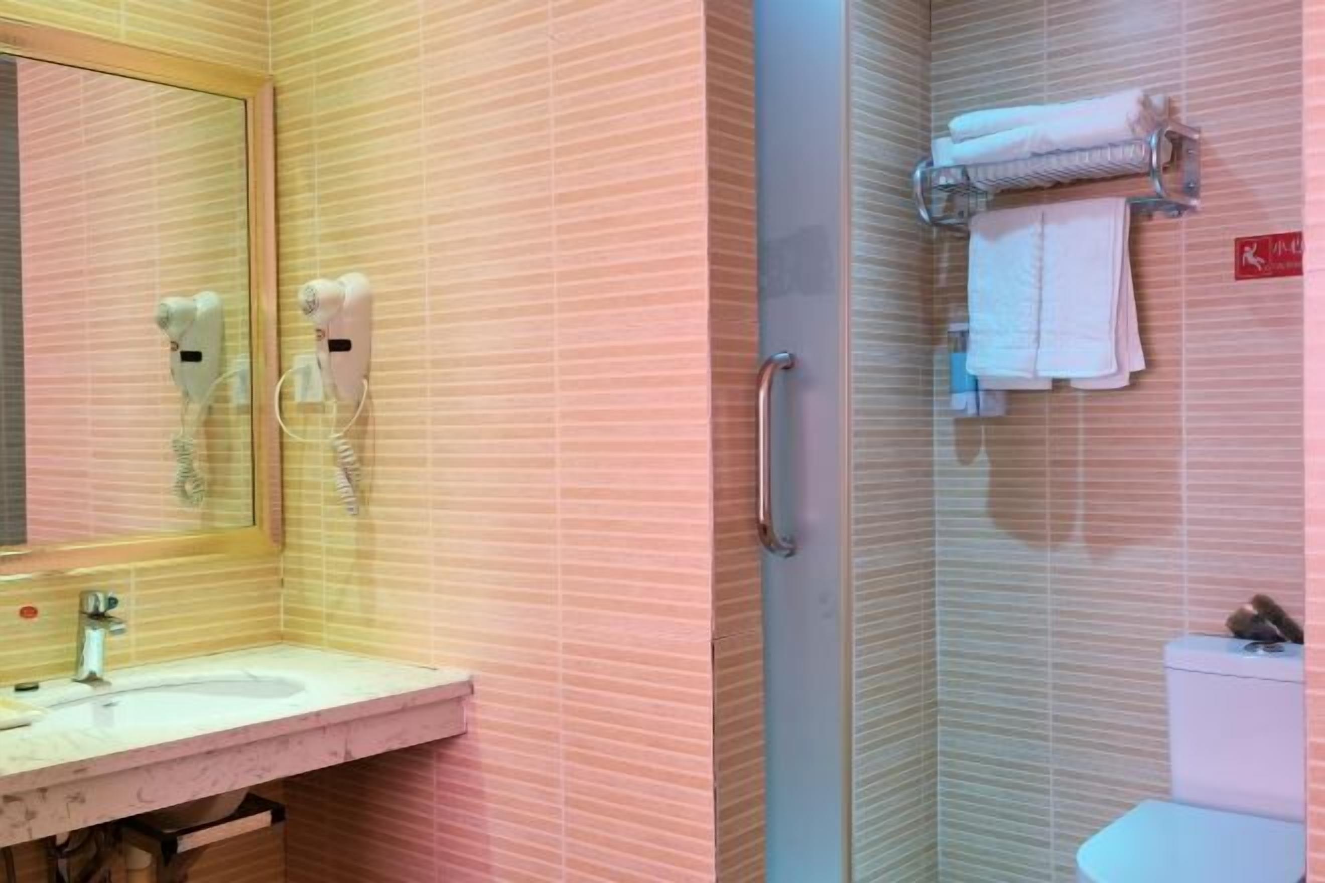 Un baño con lavabo, espejo, secador de pelo, toallero y retrete.