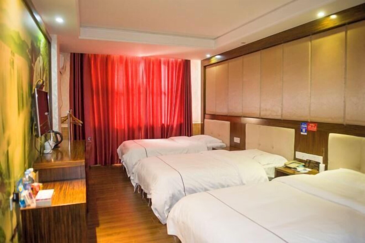 A hotel room with two beds, a wooden desk, and a red curtain.