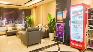 A hotel lobby with sofas, a potted plant, a vending machine, and a cityscape view. - Fubang Hotel (Yichun)