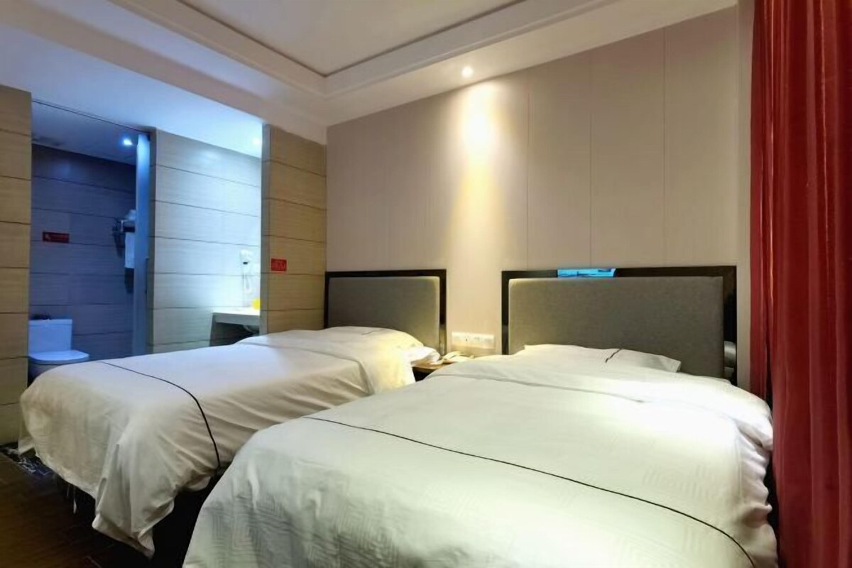 A hotel room with two beds, a bathroom, and a red curtain.