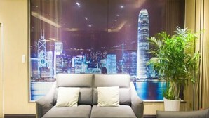 A modern living room with a sofa and a large window displaying a cityscape. - Fubang Hotel (Yichun)