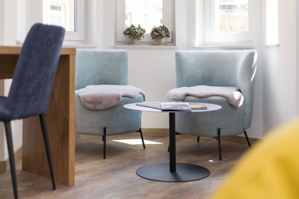 A room with two armchairs, a small round table, and a wooden chair. - Gasthaus zur Traube (Uffenheim)