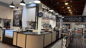 A coffee shop interior with a counter, coffee machines, and a menu board.