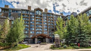 A multi-story hotel with a central entrance, surrounded by trees and a parking area.