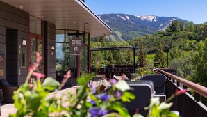 Un restaurante con terraza al aire libre con vistas a un paisaje montañoso.