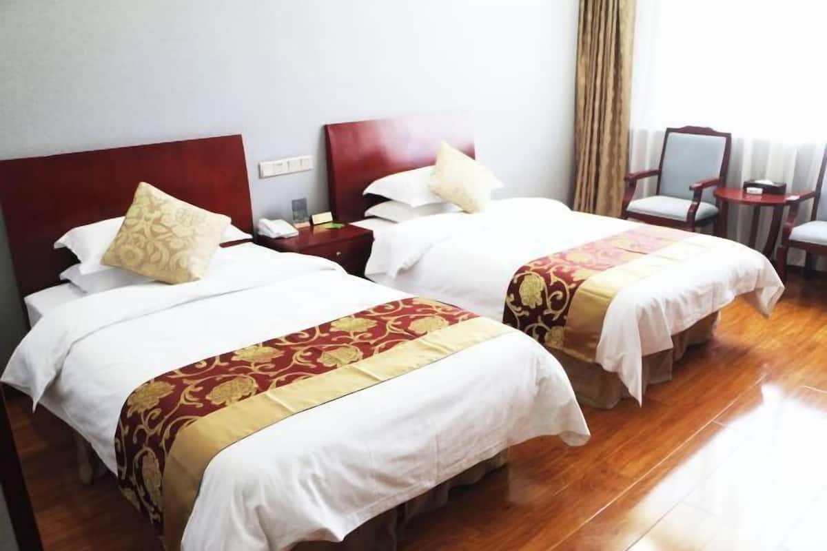 Two double beds with matching headboards, a bedside table, a chair, and a small table.