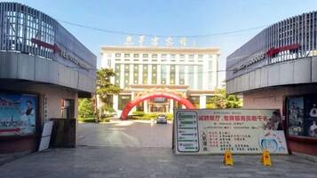 A hotel entrance with a red archway, a signboard with information, and a clear sky.