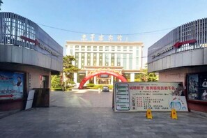 A hotel entrance with a red archway, a signboard with information, and a clear sky. - Pingliang Hotel (Pingliang)