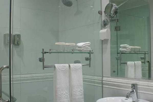 A modern bathroom with a glass shower enclosure, a large mirror, and glass shelves holding toiletries. - Pingliang Hotel (Pingliang)