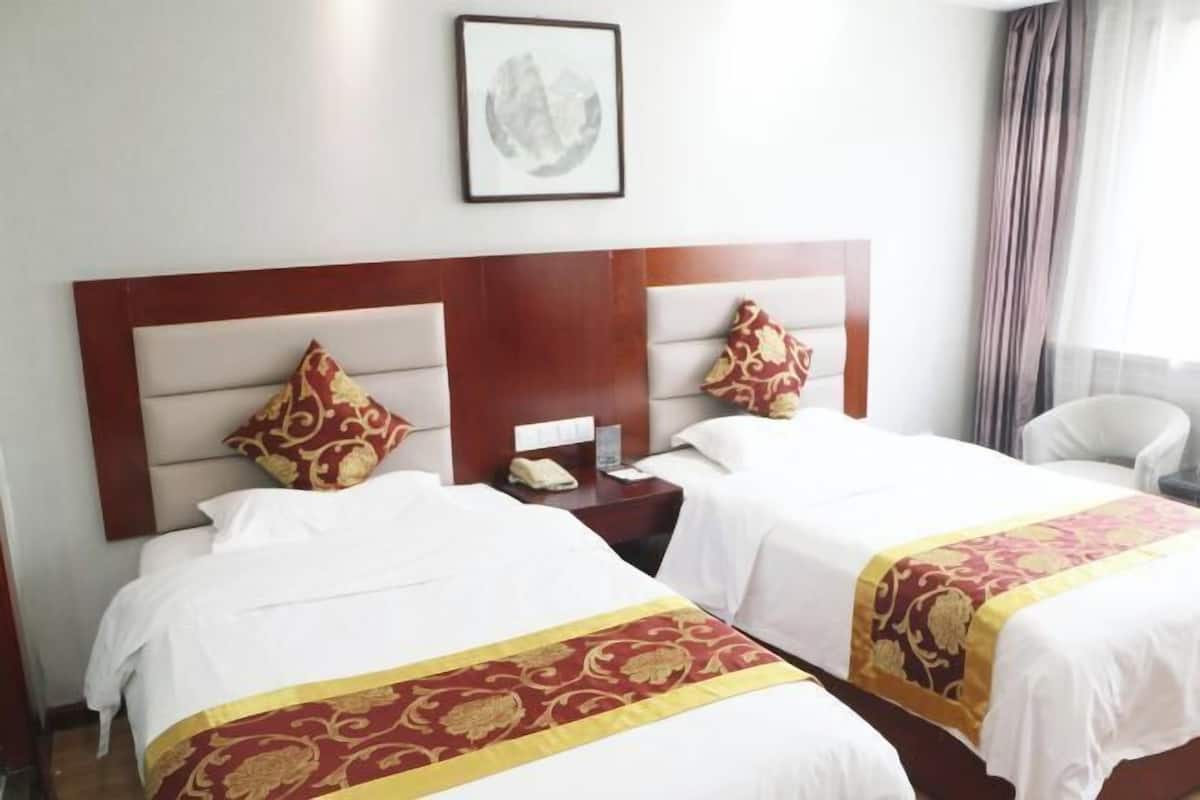 A hotel room with two beds, a nightstand, a chair, and a framed picture on the wall.