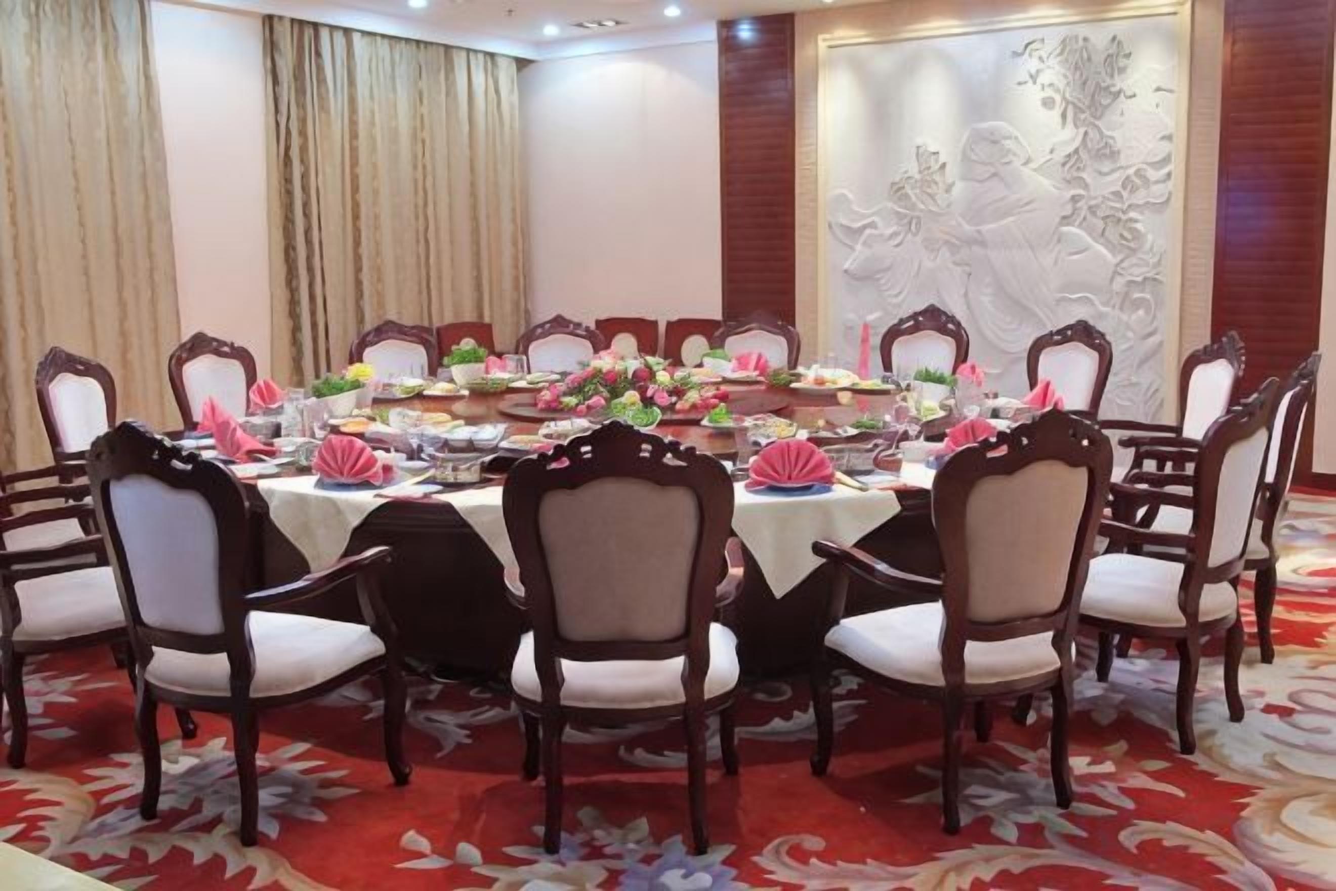 Un salón de conferencias con una mesa redonda, sillas y centros de mesa con flores.