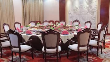 Un salón de conferencias con una mesa redonda, sillas y centros de mesa con flores.