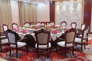 A conference room with a round table, chairs, and floral centerpieces. - Pingliang Hotel (Pingliang)