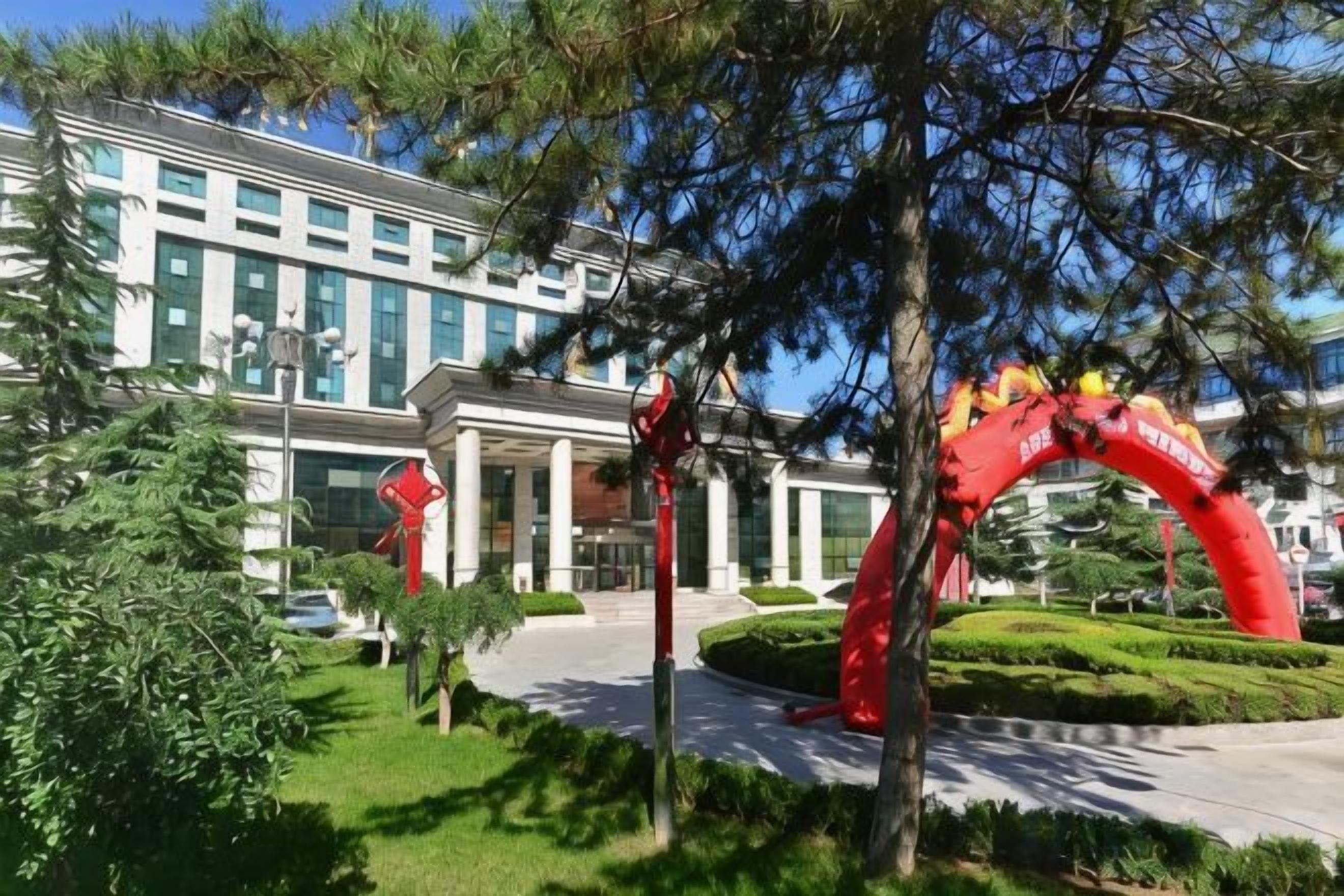 Ein Hotel mit rotem Bogenportal, einem gepflegten Rasen und einem Gebäude mit moderner Fassade.