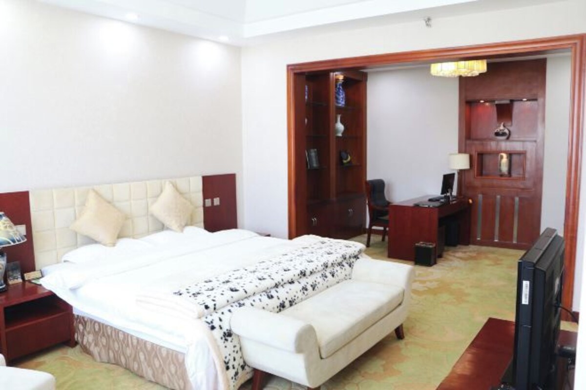 A hotel room with a bed, a desk, a television, and a wardrobe.