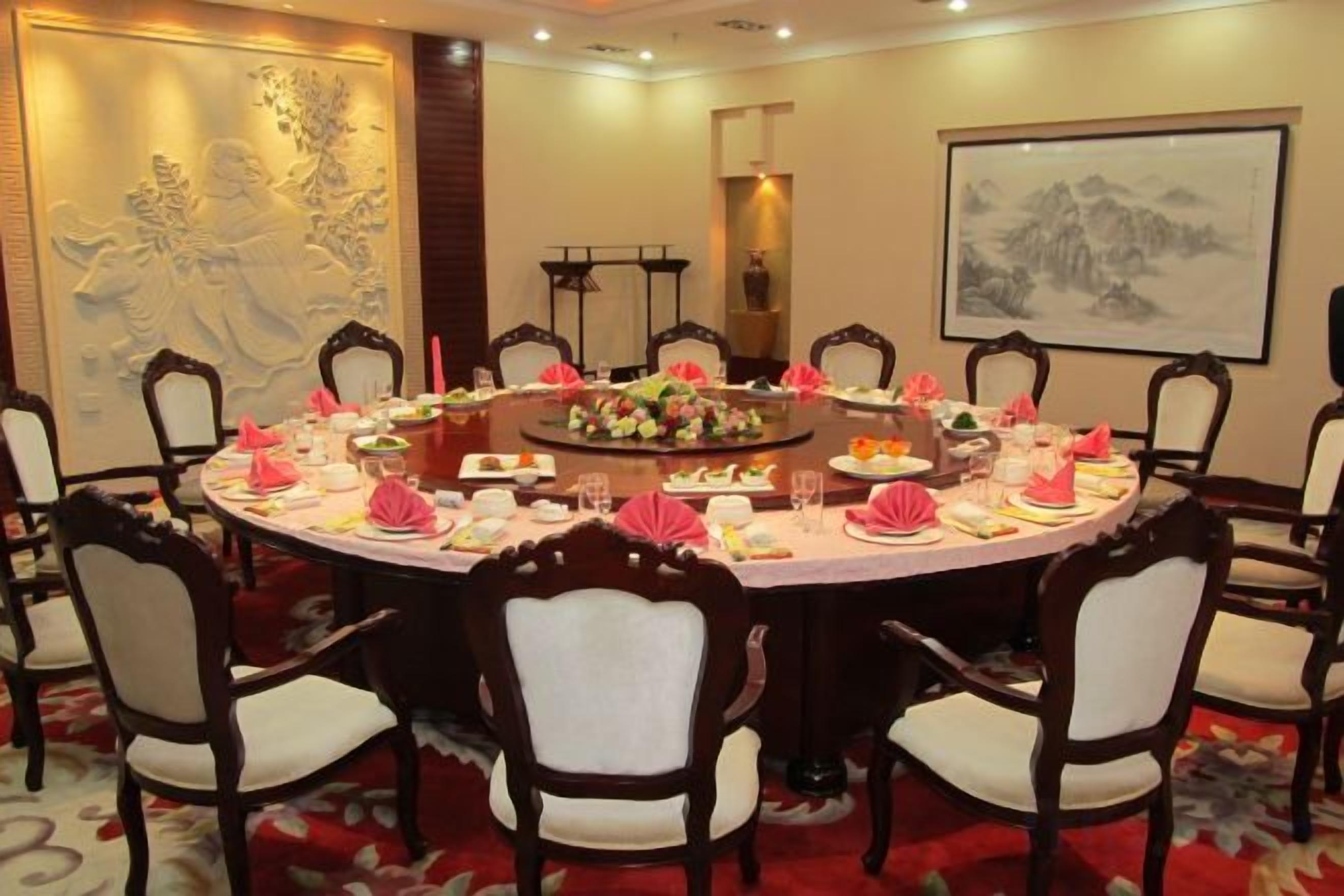 Una mesa redonda de comedor con sillas, un centro de mesa floral y una obra de arte enmarcada en la pared.