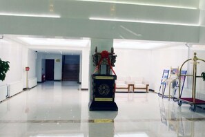 Un hall d'entrée propre et moderne, avec un comptoir d'accueil, un espace salon et un présentoir.