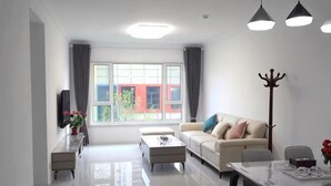 Een moderne woonkamer met een bank, salontafel, eettafel en kapstok.