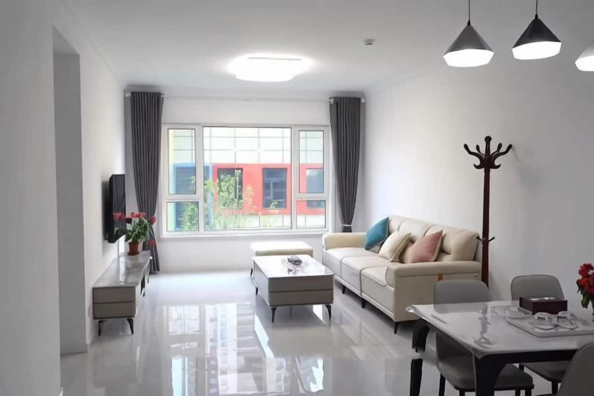 A modern living room with a sofa, coffee table, dining table, and a coat rack.