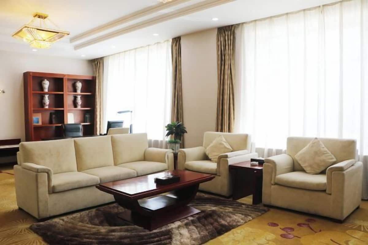 A living room with a beige sofa set, a wooden coffee table, and a small side table.