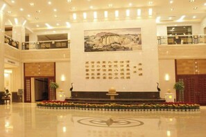 Eine geräumige Lobby mit einer zentralen Rezeption, einem großen Wandgemälde und einer Zierbrunnen.