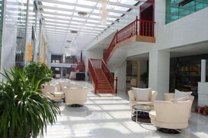 A spacious lobby with a high ceiling, a staircase, and seating areas. - Pingliang Hotel (Pingliang)