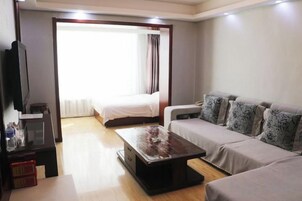 Una habitación de hotel con cama, sofá, televisión y una mesa de centro.