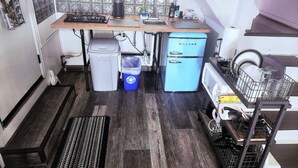Une cuisine de taille réduite, équipée d’une cuisinière à gaz, d’un petit réfrigérateur et d’un évier.