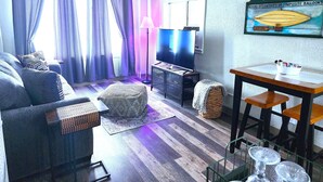 Un salon comprenant un canapé, un téléviseur, une table et un panier en osier.
